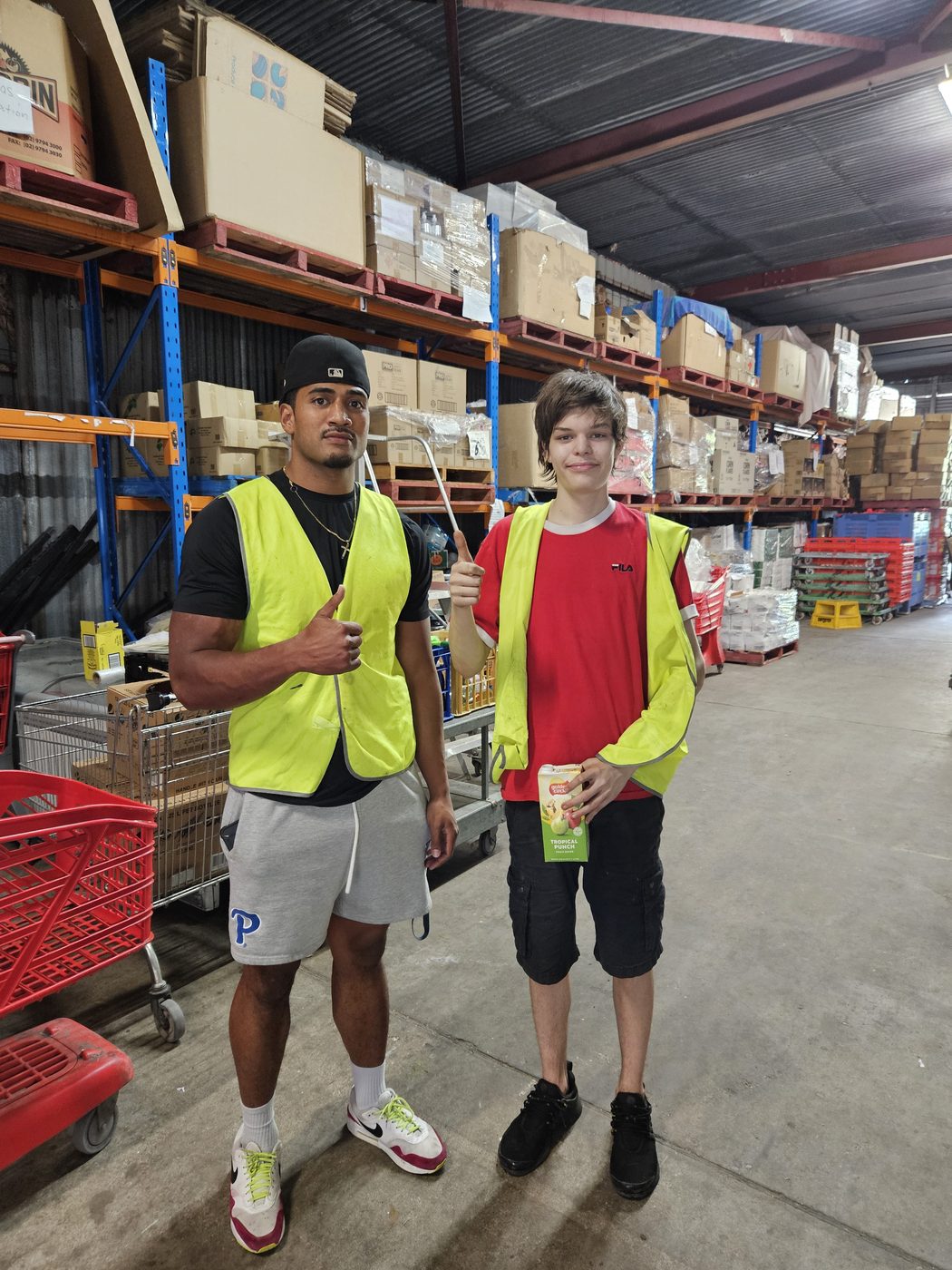 Two participants giving a thumbs up while sorting stock in the warehouse